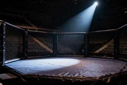 Cage octogonale de MMA vide éclairée par un projecteur dans une arène sombre