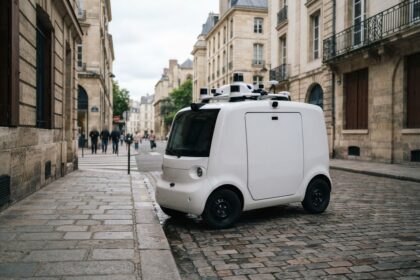 Petit véhicule de livraison électrique blanc à capteurs sur le toit, à l'arrêt dans une rue pavée