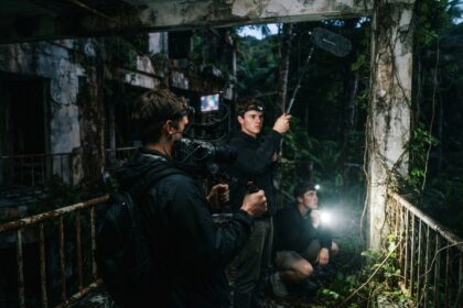 Trois jeunes filment de nuit avec caméra et perche dans un bâtiment abandonné envahi par la jungle