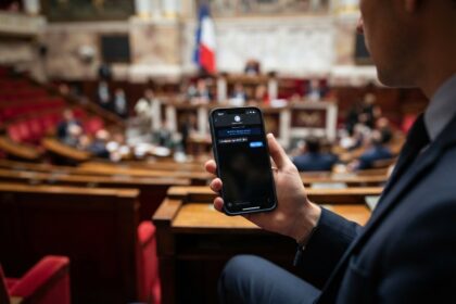 Homme en costume consultant une messagerie sur son smartphone dans l'hémicycle de l'Assemblée nationale